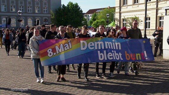 Demonstrierende mit einem Banner. Darauf heißt es: "Demmin bleibt bunt!" © Screenshot 