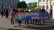Demonstrierende mit einem Banner. Darauf heißt es: "Demmin bleibt bunt!" © Screenshot 