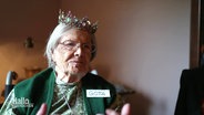 Eine Seniorin mit Namensschild "Göta" trägt eine Krone © Screenshot 
