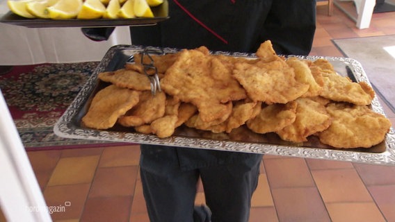 Auf einem silbernen Tablett stapeln sich Wiener Schnitzel. © Screenshot 