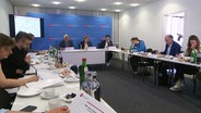 Ein Konferenzraum mit Menschen, unter anderem der niedersächsischen Innenministerin. © Screenshot 