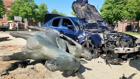 Die gestürzte Statue neben dem schwer beschädigten Auto. © Screenshot 