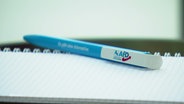 Auf einem Notizblock liegt ein Kugelschreiber mit AFD-Logo © Screenshot 
