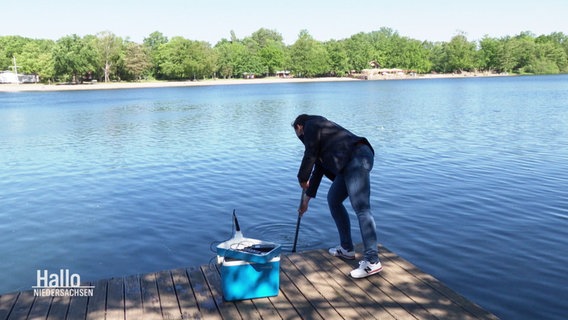 Prüferin entnimmt Wasserprobe aus einem Badesee. © Screenshot 