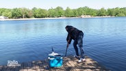 Prüferin entnimmt Wasserprobe aus einem Badesee. © Screenshot 