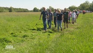 Eine Wandergruppe läuft über eine Wiese © Screenshot 