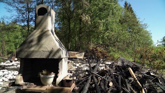 Verkohlte Überreste und Schutt der verbrannten Gartenlaube. Nur ein steinerner Grillofen steht noch. © Screenshot 
