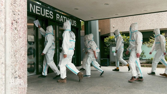 Weiß vermummte Demonstrant:innen laufen auf die Tür des Göttinger Rathauses zu. © Screenshot 