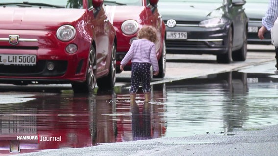 Ein kleines Kind spielt auf einer überfluteten Straße. © Screenshot 
