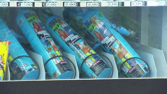Bunt bedruckte Dosen mit Lachgas liegen in einem Snackautomaten. © Screenshot 