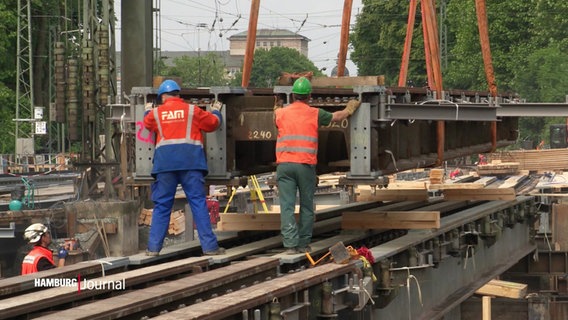 Auf der Baustelle: Arbeiter positionieren Elemente der Hilfsbrücken am Ferdinandstor. © Screenshot 