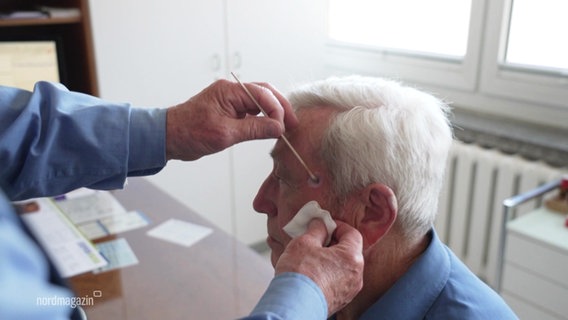 Ein älterer Mann wird von einem Dermatologen untersuch. © Screenshot 