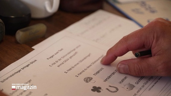 Eine Person fährt mit dem Zeigefinger an Buchstaben und Wörtern auf einem Aufgabenblatt zum Lesenlernen entlang. © Screenshot 