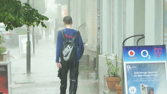 Eine komplett durchnässte Person, die durch strömenden Regen läuft, von hinten gesehen. © Screenshot 