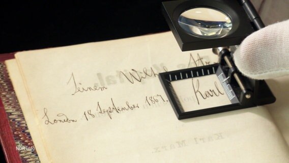 Eine handschriftliche Widmung von Karl Marx in der Erstausgabe von "Das Kapital". Eine Lupe vergrößert den Namen "Karl". © Screenshot 