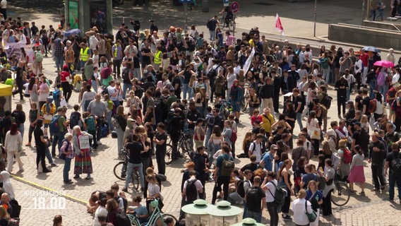 Schülerinnen und Schüler versammeln sich auf einem Platz. Einige tragen Fahnen oder Schilder bei sich. © Screenshot 