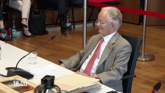 Staatskanzleichef Jörg Mielke während der Befragung. Er sitzt zurückgeöehnt an einem Tisch, vor ihm ein Mikrofon und ein Stapel Unterlagen. © Screenshot 