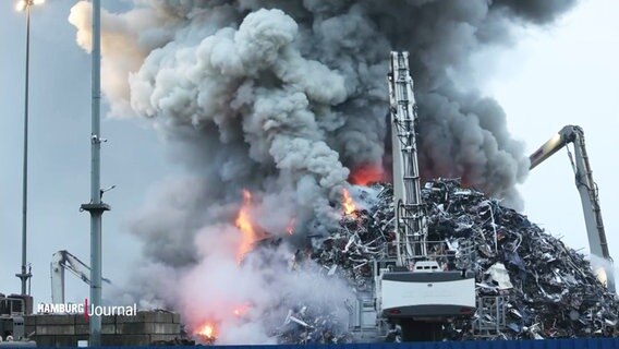 Zwei Bagger versuchen einen brennenden Schrottberg abzutragen, bevor sich die Flammen noch weiter ausbreiten können. © Screenshot 