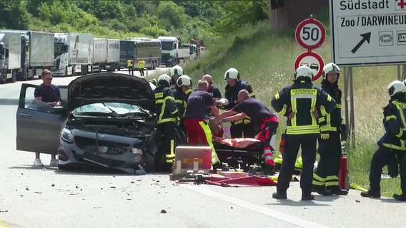 Einsatzkräfte der Feuerwehr bergen einen Verletzten aus einem Pkw. © Screenshot 