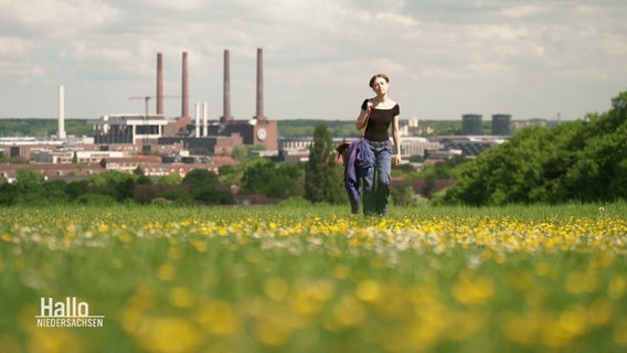 Aktivistin Clara Mayer läuft über eine Wiese, im Hintergrund die VW-Werke. © Screenshot 