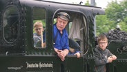 Ein Mann in blauerkleidung in einer Dampflokomotive. © Screenshot 