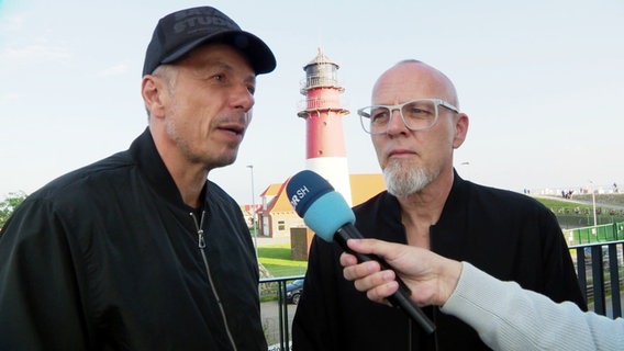 Michael Beck und Thomas D im Interview. Hinter ihnen ragt der Büsomer Leuchtturm empor. © Screenshot 