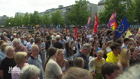 Blick auf eine Menge von Menschen. Einige halten Flaggen, darunter die EU-Flagge hoch. © Screenshot 