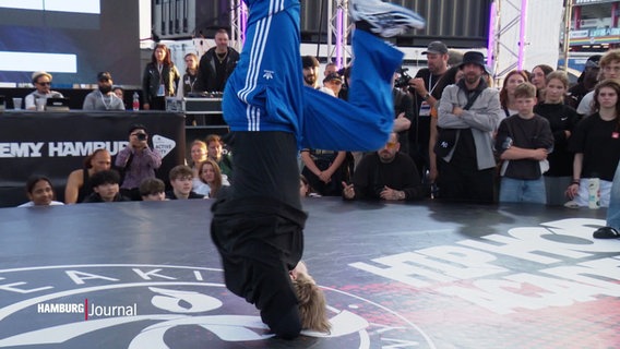 Ein Breaker tritt mit seiner Tanzperformance auf einer runden Plattform auf. © Screenshot 