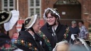 Zwei Frauen in traditionellen Trachten lächeln sich zu. © Screenshot 