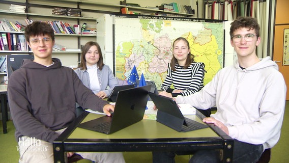 Vier Schülerinnen und Schüler an einem Tisch in einem Klassenzimmer. © Screenshot 