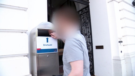 Ein Mann fasst in einen Briefkasten für Briefwahl-Umschläge in Hamburg-Altona. © Screenshot 