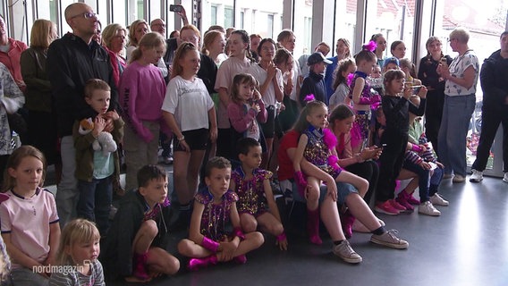 Bunt und pink angezogene Kinder haben sich für ein Gruppenfoto aufgestellt. © Screenshot 