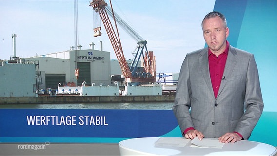 Ein Nordmagazin-Moderator steht vor einer Leinwand die eine Werft zeigt. © Screenshot 