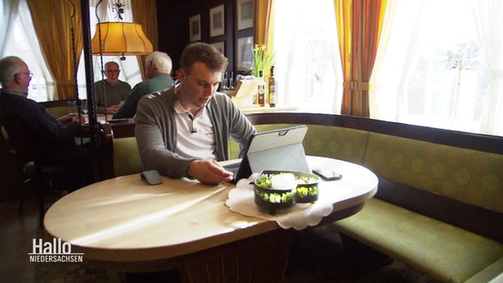Der Start-up-Gründer Martin Meyer sitzt mit seinem Laptop an einem Tisch in einer Kneipe. © Screenshot 