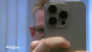 Ein junger Mann hinter seinem Smartphone. © Screenshot 