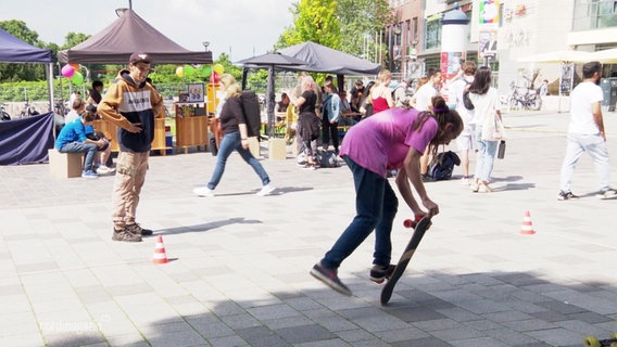 Auf einem Platz macht ein Jugendlicher gekonnte Tricks mit seinem Skateboard. © Screenshot 