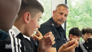 Ein Polizeibeamter sitzt gemeinsam mit Jugendlichen in einem Sitzkreis. © Screenshot 