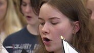 Bei einer Chorprobe: Eine singende junge Frau. © Screenshot 