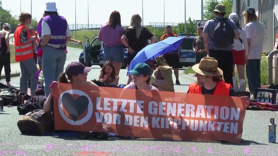 Mitglieder der "letzten Generation" halten ein Banner mit der Aufschrift: "Letzte Generation vor den Kippunkten". © Screenshot 