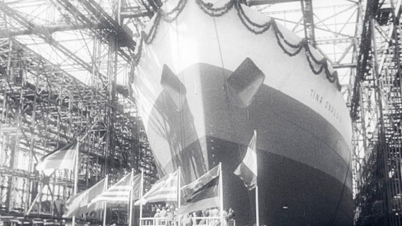 Eine alte schwarz-weiß Videoaufnahme. Ein großer, geschmückter Tanker läuft aus der Werft. Es ist der Tanker "Tina Onassis". © Screenshot 