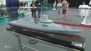 Schiffsmodell in einer Glasvitrine mit dem Logo der Damen-Werft. © Screenshot 