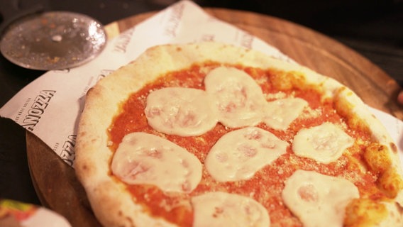 Eine ofenfrische Pizza ist mit einer veganen Mozzarella-Alternative belegt. © Screenshot 