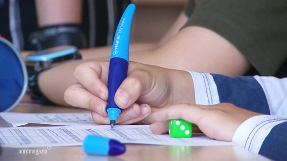 Eine Kinderhand hält einen Kinderfüller und schreibt in ein Schulheft. © Screenshot 