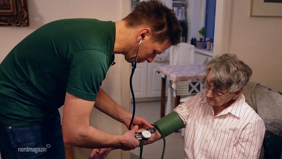 Sören Runge misst während eines hausbesuchs den Blutdruck einer alten Frau. © Screenshot 