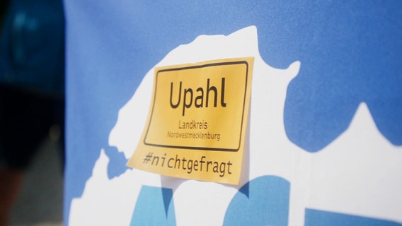 Ein gelber Aufkleber mit der Aufschrift "Upahl #nichtgefragt" auf blauem Hintergrund © NDR 