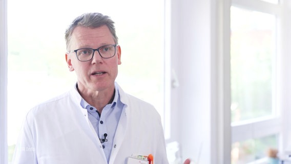 Olav Kraufse von der Diakovere Henriettenstift Hannover im Interview. Er trägt kurze graue Haare, eine Brille und einen weißen Arztkittel. © Screenshot 