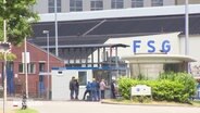 Vor dem Fördnerhaus am FSG-Gelände stehen mehrere Arbeiter. © Screenshot 