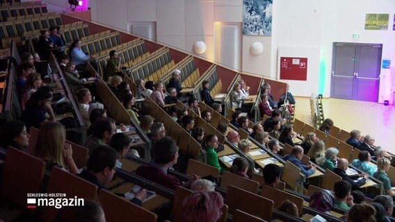 Blick von oben in die Sitzreihen eines vollen Hörsaales an der Universität Lübeck. © Screenshot 