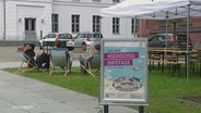 Menschen sitzen am Universitätscampus in Greifswald. © Screenshot 