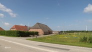 Unter blauem Himmel liegt ein Dänisches Gehöft in einer weiten, flachen, grünen Landschaft. © Screenshot 